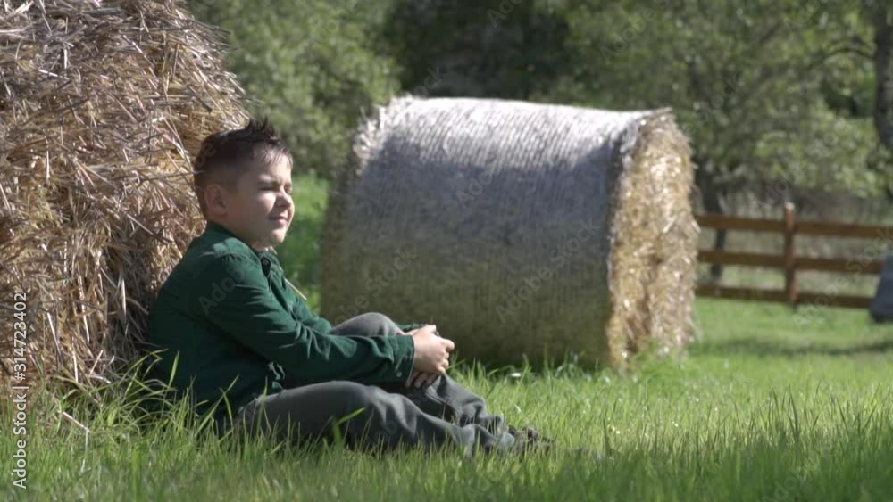 A young boy looks at the rays of the sun sitting on the grass. A young boy looks at the rays of the sun sitting on the grass.