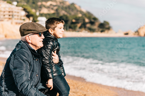 Grandfather and grandson enjoying a beach day in winter