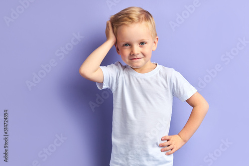 Honey little boy posing isolated over purple background, looking at camera. Portrait