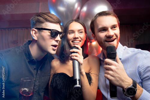 young caucasian people celebrating birthday in karaoke bar, chill out. holiday, celebration, party concept. emotional pastime