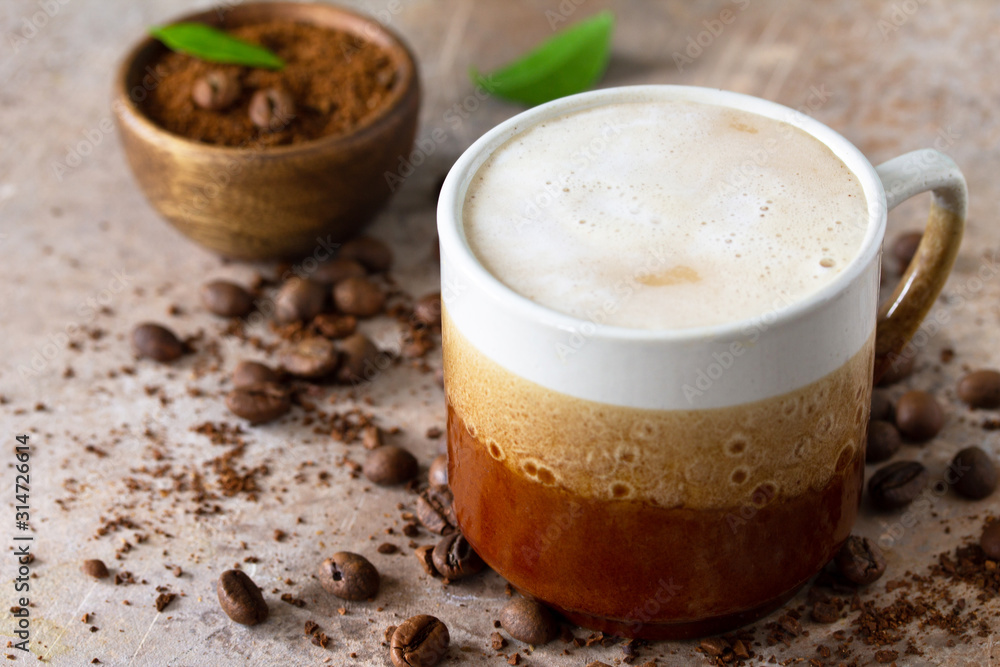 Morning coffee concept. Cup of coffee latte, coffee beans and ground powder on a stone old concrete countertop. Morning coffee concept. Cup of coffee latte, coffee beans and ground powder on a stone old concrete countertop.