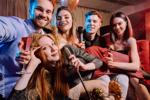 group of young people gathered to sing songs in karaoke bar, enjoy celebration of birthday in karaoke, young guys and ladies together at party