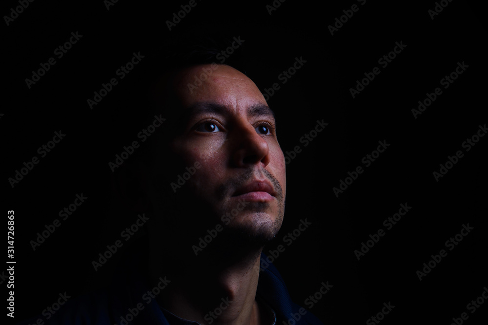 portrait of a young guy in low key on a black background portrait of a young guy in low key on a black background