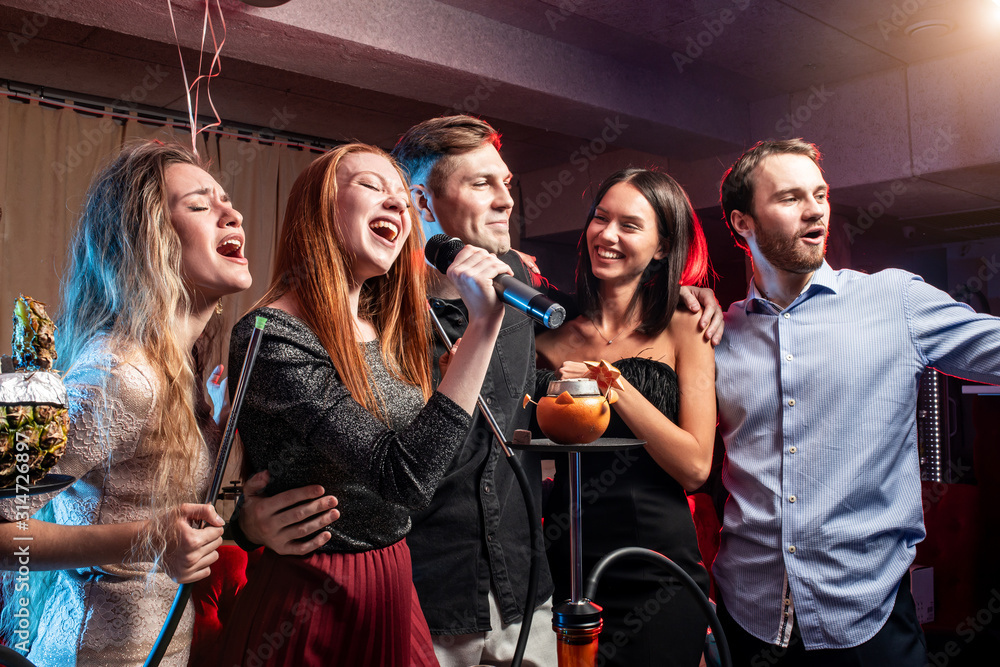 young ladies and guys chilling and rocking in karaoke bar, spend day-off in  karaoke together with friends, enjoy time in club foto de Stock | Adobe  Stock