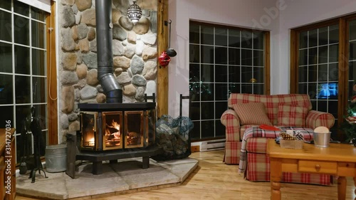 Wood stove fireplace with metal body and glass door in house with cozy interior