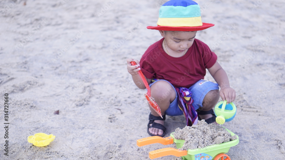 Fototapeta premium Cute baby boy playing with beach toys on tropical beach happy kid outdoor holiday.