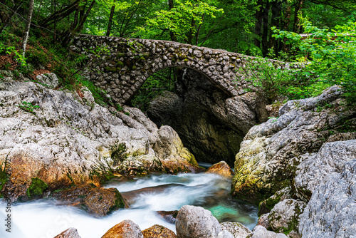 Bach mit alter Steinbrücke Bäume im Hintergrund Wasser Langzeitbelichtung photo