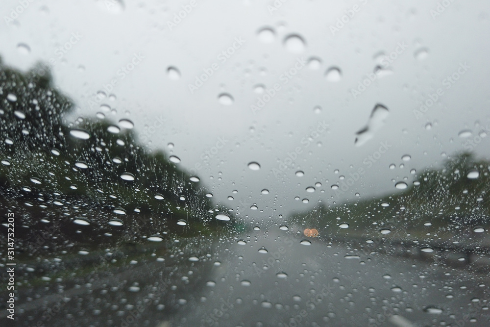Rain drop falling on car windshield, drive car on street in city in heavy rain Rain drop falling on car windshield, drive car on street in city in heavy rain