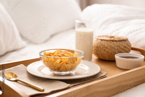 Corn flakes and milk in tray on bed. Delicious morning meal