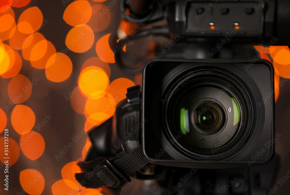 Modern video camera against blurred lights, closeup
