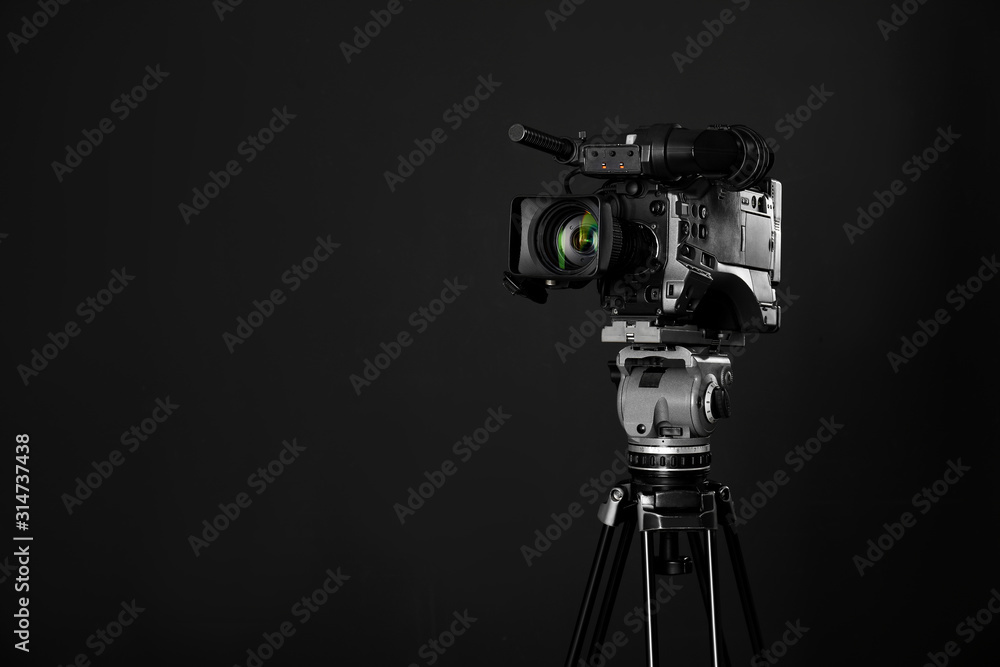 Modern professional video camera on black background. Space for text