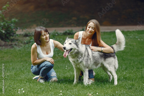 Beautiful girls in a white t-shirt. Women in a summer park. Lady with a dog © hetmanstock2