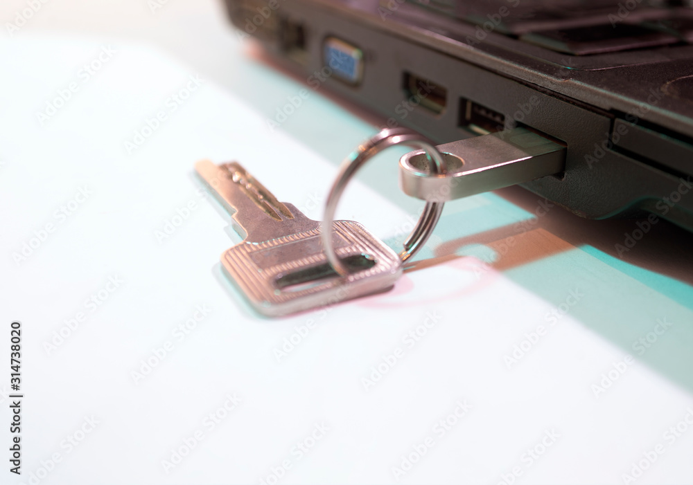 The key to the lock and a flash drive on the USB output of the laptop. White background. The key to the lock and a flash drive on the USB output of the laptop. White background.