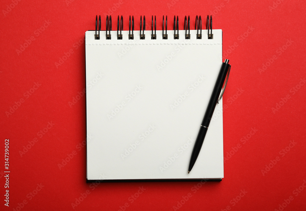 Stylish open notebook and pen on red background, top view Stylish open notebook and pen on red background, top view