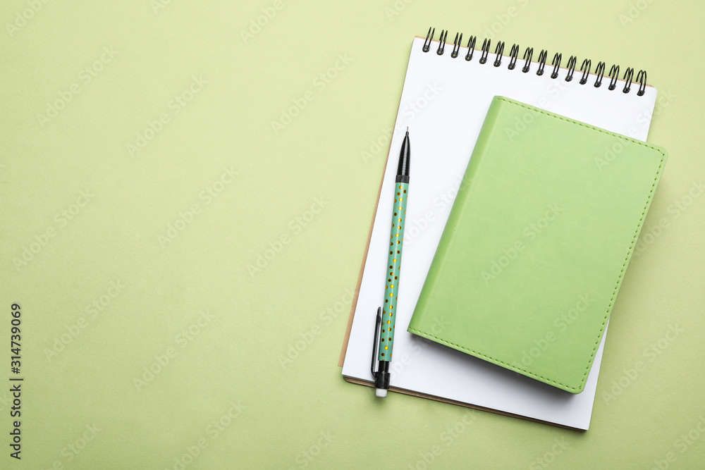 Stylish notebooks and pencil on light green background, top view. Space for text - obrazy, fototapety, plakaty 