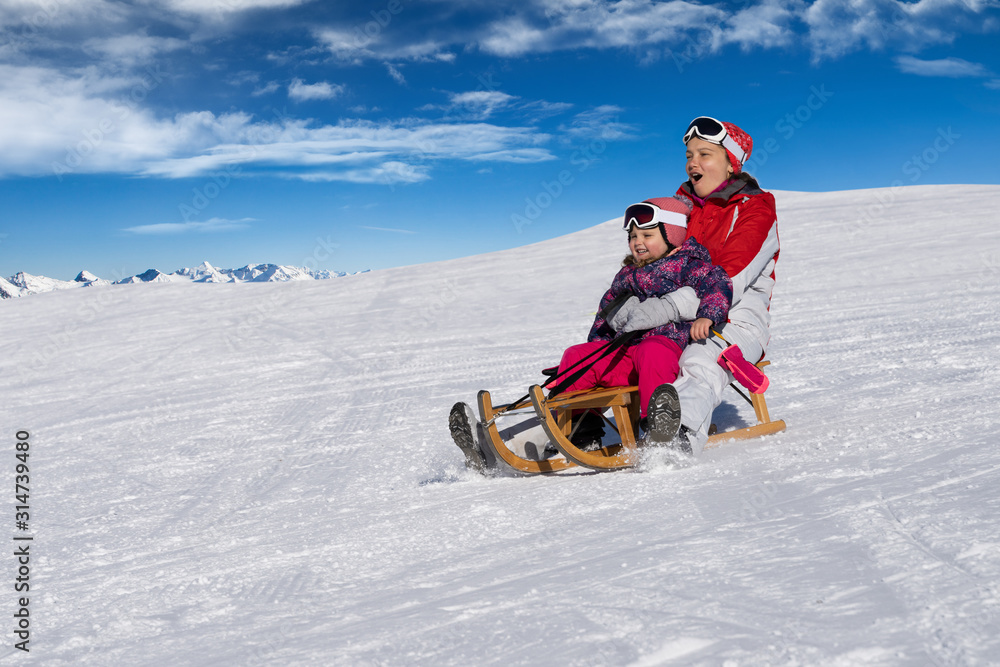 Mother And Daughter Enjoying Sledge Ride In Winter Park