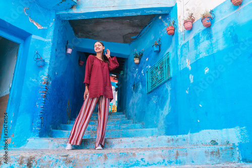 blue city of morocco, a staircase in the tunnel leading up, on it stands a girl in a shirt and striped pants © mnelen.com