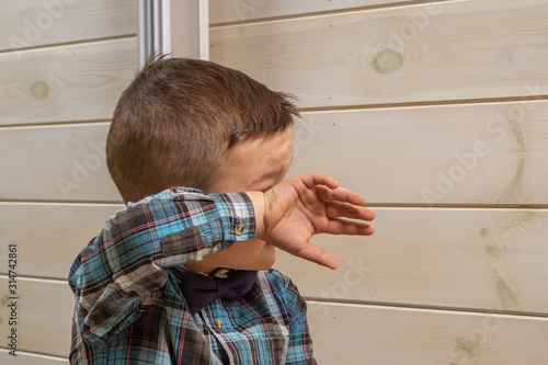Bild auf Leinwand A 4 years old boy in a blue clerical shirt is crying on a light wooden background