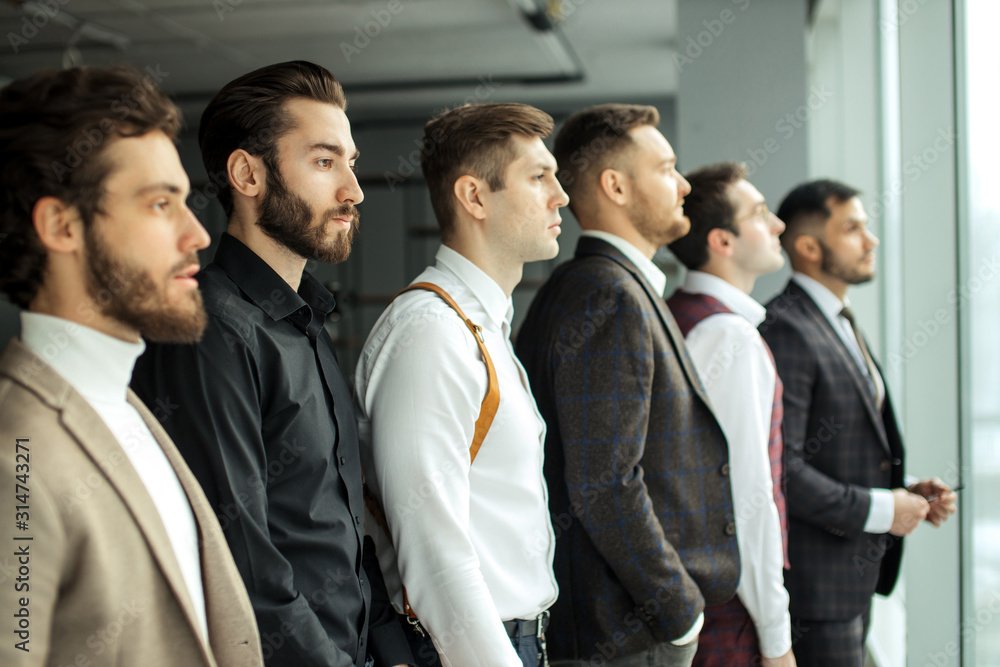 side view on young caucasian bearded business men looking side at window, everyone in stylish elegant tuxedo. isolated in modern office