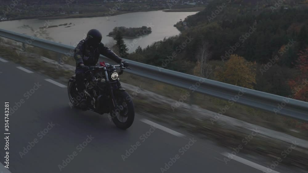 Rolling shot man riding fast a motorcycle on a mountain highway. Motorcycle rider racing his motorcycle on mountain road. Young man riding motorbike during trip. Concept of freedom and ride adventure Rolling shot man riding fast a motorcycle on a mountain highway. Motorcycle rider racing his motorcycle on mountain road. Young man riding motorbike during trip. Concept of freedom and ride adventure