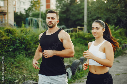 Fototapeta Naklejka Na Ścianę i Meble -  Couple training. Guy in a sports shorts. Girl in a summer park