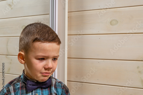 Bild auf Leinwand A 4 years old boy in a blue clerical shirt is crying on a light wooden background