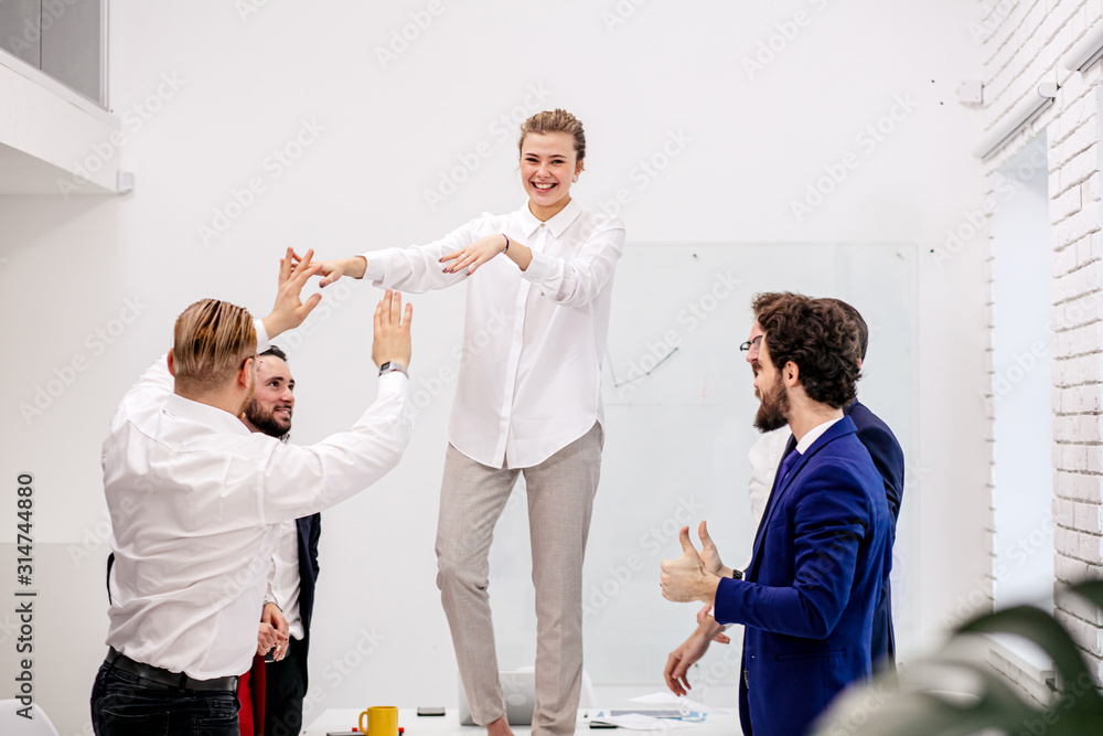 Obraz premium young happy caucasian team celebrate victory in modern office, after successful win or completion of project, togetherness of business team