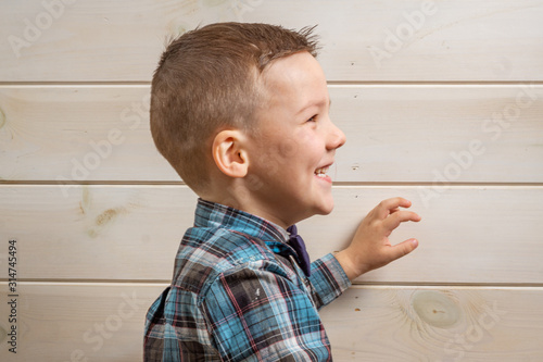 Foto A 4 years old boy in a blue clerical shirt is crying on a light wooden background