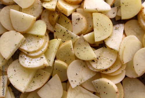 Round  spiced slices of raw white  potatoes before grilling in the owen. Top view.