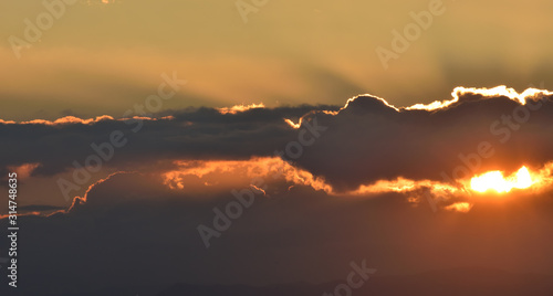 Solar disk hovering between clouds at sunset