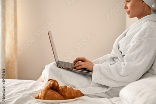 Woman in bathrobe typing on laptop.