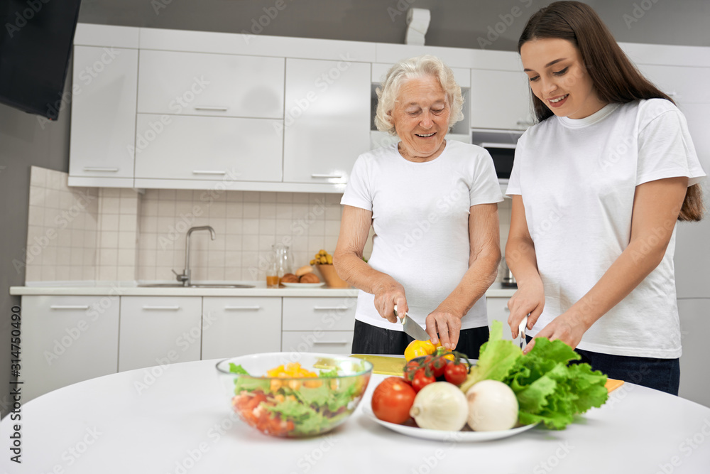Senior woman cooking salad with granddaughter. Senior woman cooking salad with granddaughter.