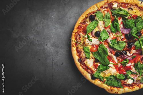 greek chicken pizza on black stone background with copy space. top view