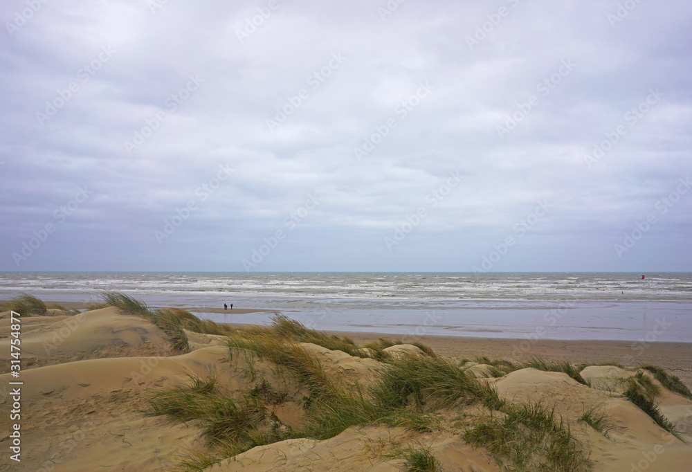 Sea, sand dunes, low tide silhouettes of two people by the water. Camber Sands, England Sea, sand dunes, low tide silhouettes of two people by the water. Camber Sands, England