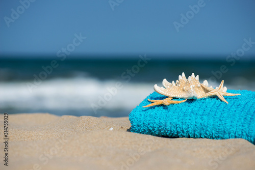 Fototapeta Naklejka Na Ścianę i Meble -  Summer vacation concept  towel with sunglasses and starfish on sandy tropical beach - selective focus, copy space