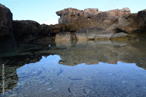 roca reflejada en las tranquilas y cristalinas del mar mediterraneo