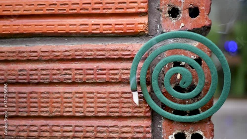 Mosquito repellent coil smokes on orange color brick wall photo