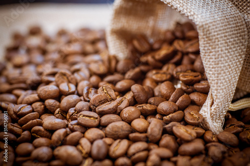 Black roasted coffee beans in a bag.  Coffee beans spilled out of a small bag.