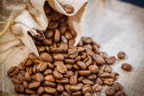 Cafe beans get enough sleep from their bag on a sackcloth background. Black coffee beans close-up. Roasted coffee beans background.