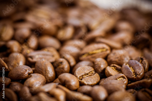 Black coffee beans close-up. Roasted coffee beans background. Brown coffee beans isolated on burlap background.