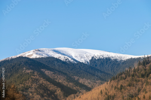 Photo of the Iezer-Papusa mountains with their snowy peaks and the orange nature took at Rausor Lake and Dam, Arges, Romania © Ehcalahim