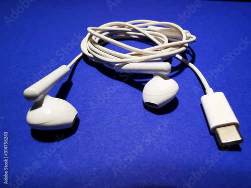 White headphones for a smartphone or an MP3 player with loud and quiet switch on blue background