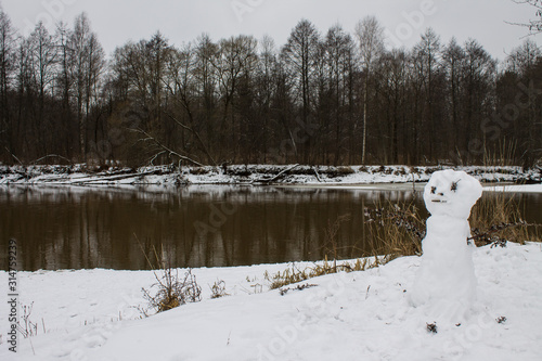 Winter landscape with snowman river and reflections and snow on the Bank on a cloudy day