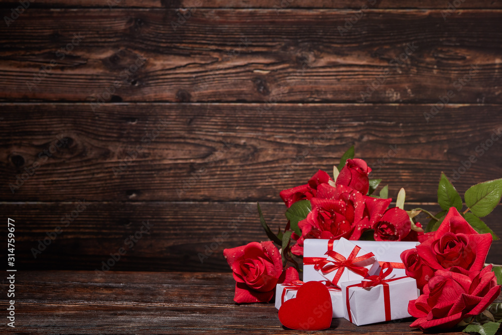 Red roses, decorative hearts, gift boxes on dark brown wooden background with copy space. Valentine's Day, wedding day Red roses, decorative hearts, gift boxes on dark brown wooden background with copy space. Valentine's Day, wedding day