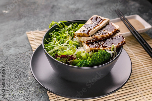 Vegan menu. Pan-Asian cuisine. Tofu with teriyaki sauce, lettuce, green beans and cauliflower in a bowl, nutty spicy sauce photo