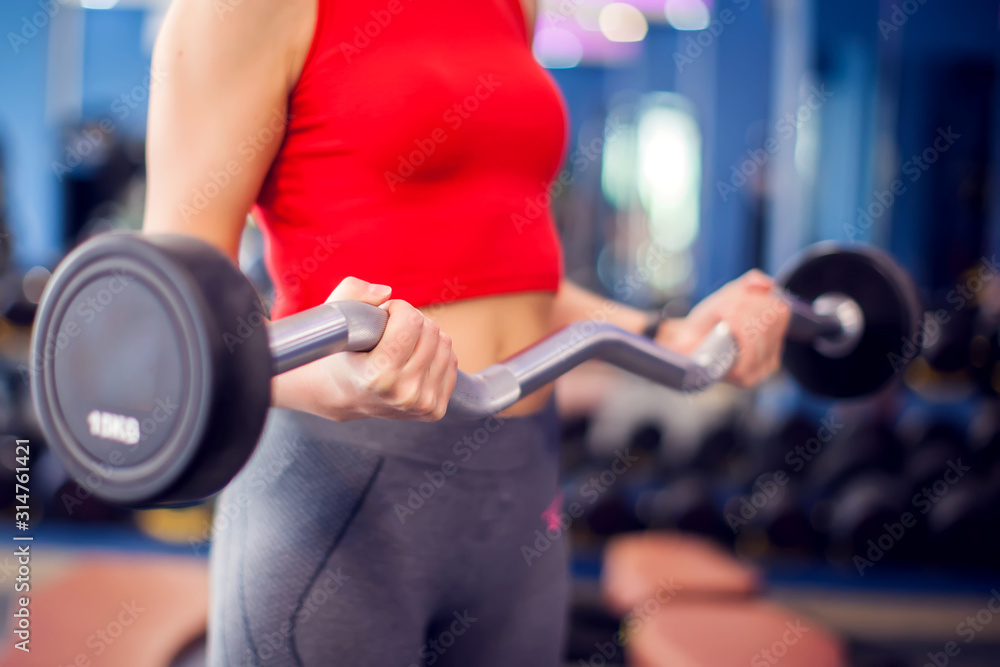 Woman in red top training bicep in gym. People, fitness and lifstyle concept