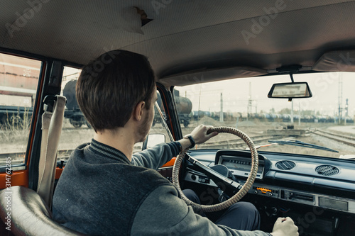 young happy man in oldschool car driving near the train