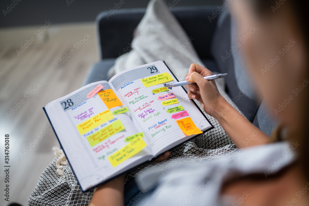Fototapeta premium Woman Making List Of Office Work In Diary