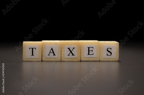 The word TAXES written on  wooden cubes isolated on a black background photo