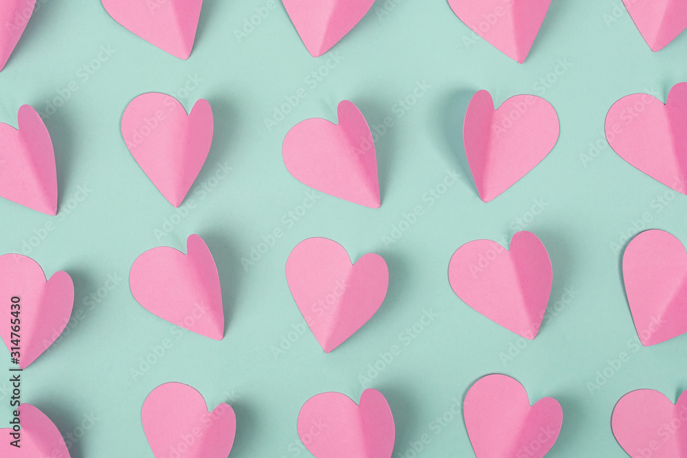Seamless romantic background made of pink paper hearts on mint color background. Flat lay. Top view